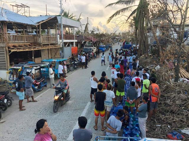 In this file photo taken on December 23, 2021, shows residents with their water plastic containers queueing up to receive free drinking water at a village in General Luna town, Siargao island, days after super Typhoon Rai devastated the island. Survivors of a deadly 2021 typhoon in the Philippines filed a UK lawsuit against British oil giant Shell, seeking financial compensation for climate-related devastation, three NGOs supporting claimants announced December 11. (Photo by ROEL CATOTO / AFP)