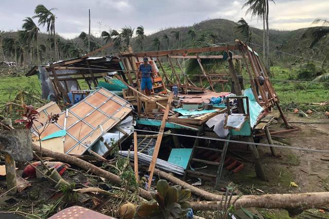 In this file photo taken on December 22, 2021, shows a resident standing on the remains of his wrecked house at a village in Dapa town on Siargao island, days after Super Typhoon Rai barelled through the island. Survivors of a deadly 2021 typhoon in the Philippines filed a UK lawsuit against British oil giant Shell, seeking financial compensation for climate-related devastation, three NGOs supporting claimants announced December 11. (Photo by ROEL CATOTO / AFP)