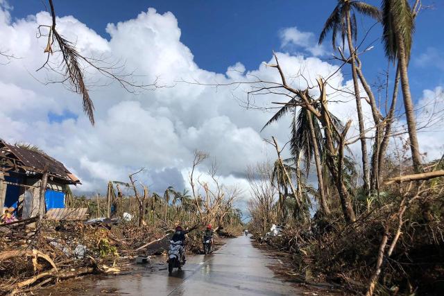 In this file photo taken on December 20, 2021, shows motorists speeding past fallen coconut trees at the height of Super Typhoon Rai along a highway in Del Carmen town, Siargao island, days after Super Typhoon Rai hit the province. Survivors of a deadly 2021 typhoon in the Philippines filed a UK lawsuit against British oil giant Shell, seeking financial compensation for climate-related devastation, three NGOs supporting claimants announced December 11. (Photo by ROEL CATOTO / AFP)