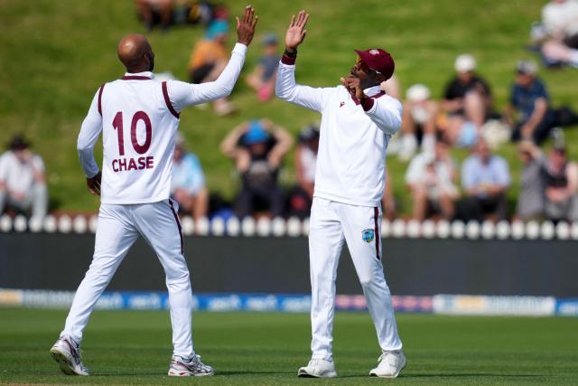 West Indies' Justin Greaves (R) and teammate Roston Chase (L) celebrate New Zealand' Glenn Phillips being run out during day two of the 2nd international Test cricket match between New Zealand and West Indies at the Basin reserve in Wellington on December 11, 2025. (Photo by Marty MELVILLE / AFP)