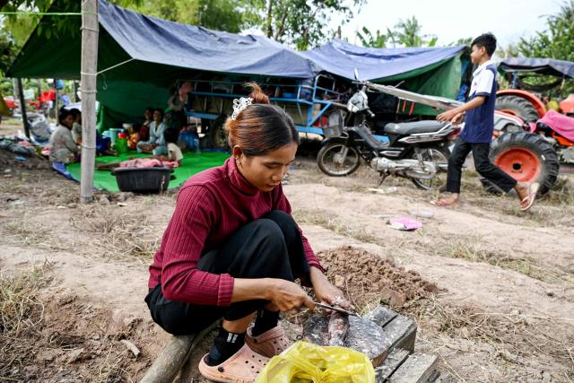A displaced resident prepares food at a temporary camp set up at a pagoda during clashes along the Cambodia-Thailand border in Cambodia's Siem Reap province on December 11, 2025. Renewed fighting raged at the border of Cambodia and Thailand on December 11, with combat heard near centuries-old temples, ahead of an expected phone call from US President Donald Trump to the two nations' leaders. (Photo by TANG CHHIN Sothy / AFP)
