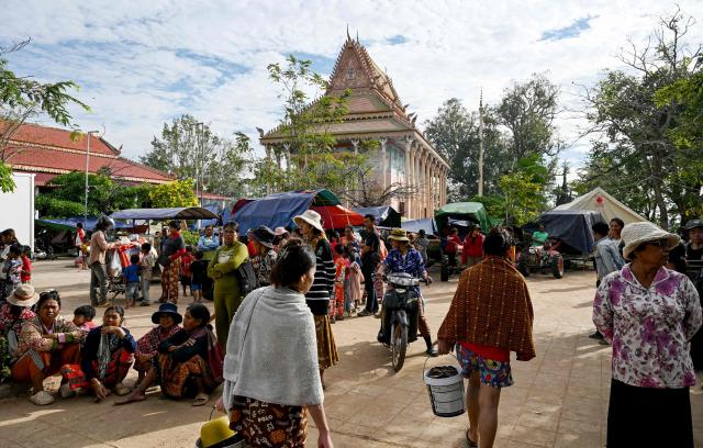 Displaced residents walk at a temporary camp set up at a pagoda during clashes along the Cambodia-Thailand border in Cambodia's Siem Reap province on December 11, 2025. Renewed fighting raged at the border of Cambodia and Thailand on December 11, with combat heard near centuries-old temples, ahead of an expected phone call from US President Donald Trump to the two nations' leaders. (Photo by TANG CHHIN Sothy / AFP)