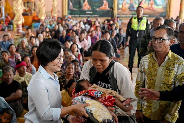 Governor of the National Bank of Cambodia Chea Serey (C-L) offers aid to a displaced resident (C) at a temporary camp set up at a pagoda during clashes along the Cambodia-Thailand border in Cambodia's Siem Reap province on December 11, 2025. Renewed fighting raged at the border of Cambodia and Thailand on December 11, with combat heard near centuries-old temples, ahead of an expected phone call from US President Donald Trump to the two nations' leaders. (Photo by TANG CHHIN Sothy / AFP)