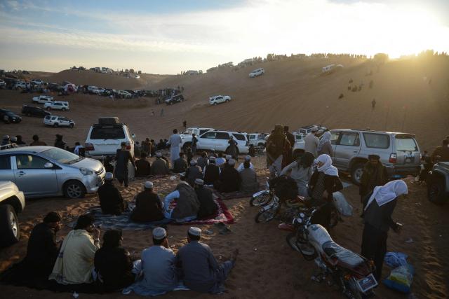 In this photograph taken on December 5, 2025, spectators watch car enthusiasts during dune bashing at the Ibrahim Khalifa Baba Shrine on a weekend in the desert of Kandahar province. On any Friday, when the Afghan weekend begins, dozens of drivers gather in the Kandahar desert to charge their SUVs up steep ochre dunes, kicking up rooster tails of sand to the delight of spectators. It's an anarchic ballet where drivers can stomp on the gas and let loose not far from the historic bastion of the Taliban. (Photo by Sanaullah SEIAM / AFP)