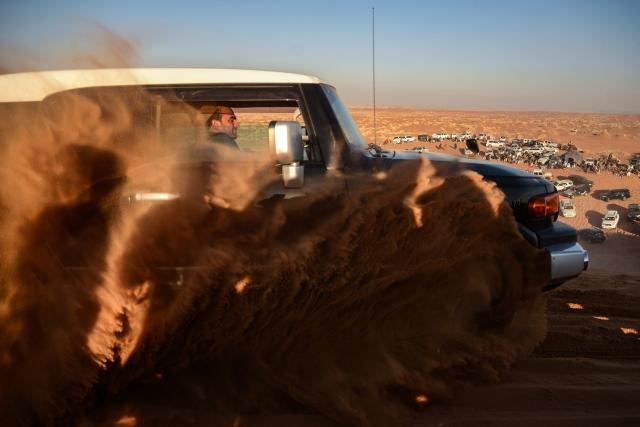 In this photograph taken on December 5, 2025, an Afghan car enthusiast drives a SUV during dune bashing at the Ibrahim Khalifa Baba Shrine on a weekend in the desert of Kandahar province. On any Friday, when the Afghan weekend begins, dozens of drivers gather in the Kandahar desert to charge their SUVs up steep ochre dunes, kicking up rooster tails of sand to the delight of spectators. It's an anarchic ballet where drivers can stomp on the gas and let loose not far from the historic bastion of the Taliban. (Photo by Sanaullah SEIAM / AFP)