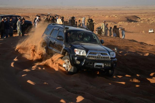 In this photograph taken on December 5, 2025, an Afghan car enthusiast drives a SUV during dune bashing at the Ibrahim Khalifa Baba Shrine on a weekend in the desert of Kandahar province. On any Friday, when the Afghan weekend begins, dozens of drivers gather in the Kandahar desert to charge their SUVs up steep ochre dunes, kicking up rooster tails of sand to the delight of spectators. It's an anarchic ballet where drivers can stomp on the gas and let loose not far from the historic bastion of the Taliban. (Photo by Sanaullah SEIAM / AFP)