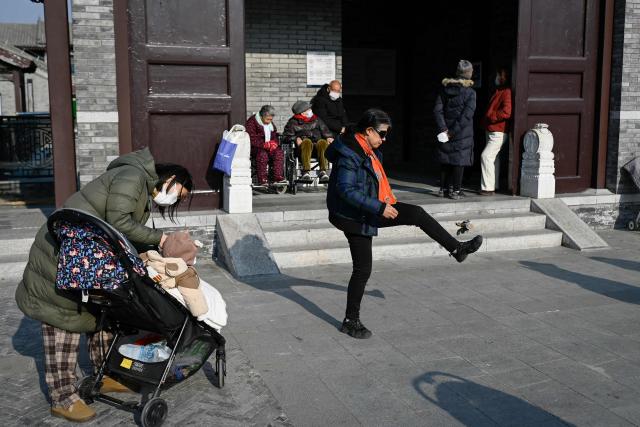 A woman kicks a shuttlecock at the entrance of a subway station in Beijing on December 11, 2025. (Photo by WANG Zhao / AFP)