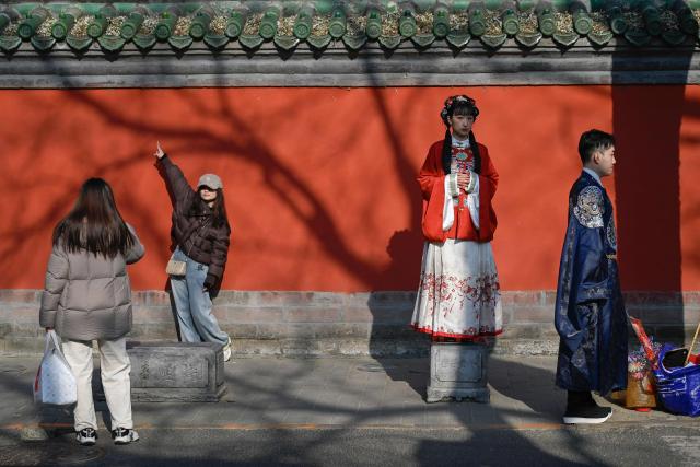 A group of people pose for pictures on a street in Beijing on December 11, 2025. (Photo by WANG Zhao / AFP)