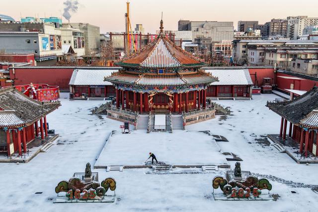 A man removes snow from a path at the Shenyang Imperial Palace after a snowfall in Shenyang, northeast China's Liaoning province on December 11, 2025 (Photo by AFP) / China OUT