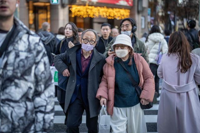 People cross a street in the Ginza area of Tokyo on December 11, 2025. (Photo by Yuichi YAMAZAKI / AFP)