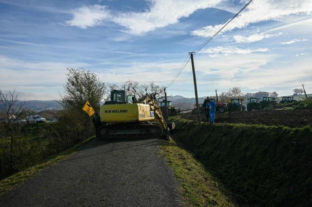 A farmer using a tractor, blocks the road with tree trunks during a protest to prevent the slaughter of a 200-cow herd, following detection of lumpy skin disease (LSD) in Les-Bordes-sur-Arize, in the Ariège department of southwestern France, on December 11, 2025. Several hundred farmers, including members of the Rural Coordination and the Farmers' Confederation, intend to prevent the cows from being euthanized, using dozens of tractors and tree trunks to block the roads leading to the farm. (Photo by Matthieu RONDEL / AFP)