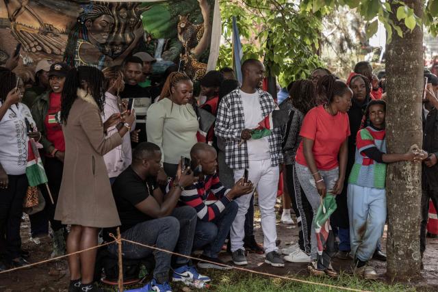 Environmental climate activist Truphena Muthoni, 22, (R) sorounded by friends and well wishers leans on a tree as she set a new Guinness World Record after hugging a tree for 72 hours without eating or sleeping, shattering her previous 48-hour record, in Nyeri on December 11, 2025. Her creative stand against deforestation, land degradation, and worsening climate shocks became a national sensation, drawing recognition from leaders and going viral across social media. (Photo by SIMON MAINA / AFP)