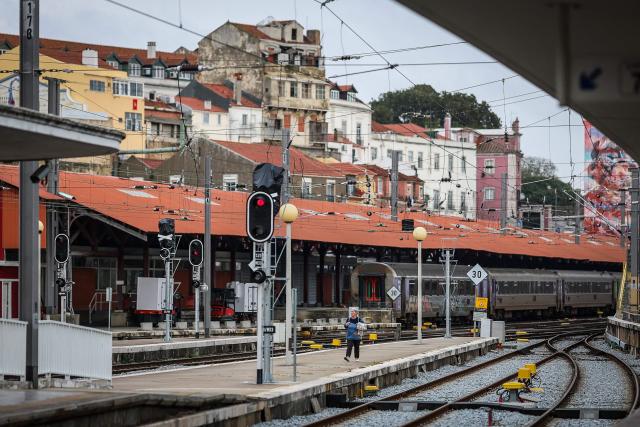 A woman stands on a platform at the Santa Apolonia train station during a general strike in Lisbon on December 11, 2025. Portugal braced on Thursday for its first general strike in 12 years, as unions urge action against the right-wing minority government's planned workers' rights reforms. Widespread disruption is expected for public transport, schools, courts and hospitals, as workers protest against a draft law aiming to simplify firing procedures, extend the length of fixed-term contracts and expand the minimum services required during a strike. (Photo by PATRICIA DE MELO MOREIRA / AFP)