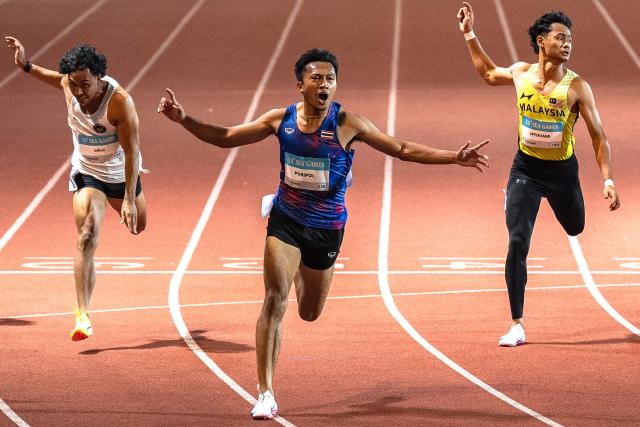 TOPSHOT - Thailand's Puripol Boonson (C) celebrates as he crosses the finish line in the men's 100m final of the athletics event during the 33rd Southeast Asian Games (SEA Games) at the Suphachalasai National Stadium in Bangkok on December 11, 2025. (Photo by Chanakarn LAOSARAKHAM / AFP)
