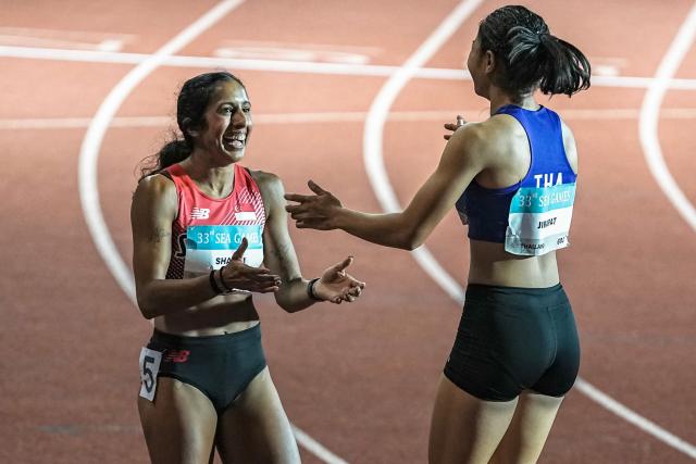 Singapore's Shanti Pereira (L) greets Thailand's Jirapat Khanonta (R) after the women's 100m final of the athletics event during the 33rd Southeast Asian Games (SEA Games) at the Suphachalasai National Stadium in Bangkok on December 11, 2025. (Photo by Chanakarn Laosarakham / AFP)