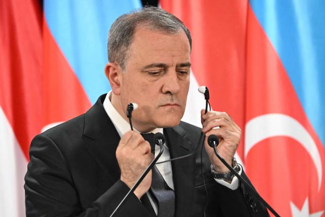 Azerbaijan's Foreign Minister Jeyhun Bayramov removes his earphones during a joint press conference with his Hungarian counterpart in the Bozsik Arena of Budapest, on December 11, 2025. Bayramov pays a working visit to the Hungarian capital, including meetings with Hungarian officials and the third Azerbaijan–Hungary Strategic Dialogue. (Photo by Attila KISBENEDEK / AFP)
