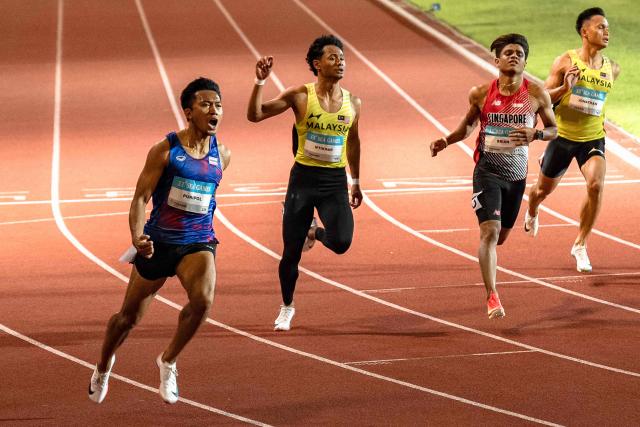 Thailand's Puripol Boonson (L) celebrates as he crosses the finish line next to Malaysia's Danish Iftikhar Muhammad Roslee (2nd L), Singapore's Marc Brian Louis (2nd R) and Malaysia's Jonathan Nyepa (R) in the men's 100m final of the athletics event during the 33rd Southeast Asian Games (SEA Games) at the Suphachalasai National Stadium in Bangkok on December 11, 2025. (Photo by Chanakarn LAOSARAKHAM / AFP)