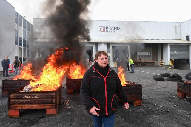 An employee stands in front of a fire at the Brandt factory, in Vendome, central France on December 11, 2025 following the verdict of the court. On December 11, 2025, the court ordered the liquidation of the century-old home-appliance group Brandt, a flagship of French industry that has been in serious trouble since it was placed under court-supervised restructuring, the president of the Centre-Val de Loire region told AFP. (Photo by JEAN-FRANCOIS MONIER / AFP)