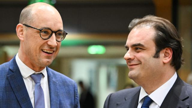 Candidates for the Eurogroup Presidency : Belgium's Finance Minister Vincent Van Peteghem (L) and Greece's  Economy and Finance Minister Kyriakos Pierrakakis (R), shake hands at the start of a meeting with finance ministers of the Eurozone to elect the new Eurogroup President and discuss the overall budgetary situation and the prospects of euro area, at the European Commission, in Brussels, on December 11, 2025. (Photo by NICOLAS TUCAT / AFP)