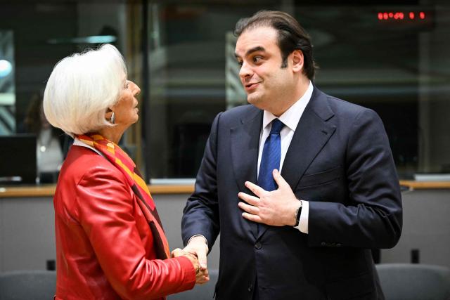 European Central Bank (ECB) President Christine Lagarde (L) shakes hands with candidate for the Eurogroup Presidency, Greece's Economy and Finance Minister Kyriakos Pierrakakis (R) at the start of a meeting with finance ministers of the Eurozone to elect the new Eurogroup President and discuss the overall budgetary situation and the prospects of euro area, at the European Commission, in Brussels, on December 11, 2025. (Photo by NICOLAS TUCAT / AFP)