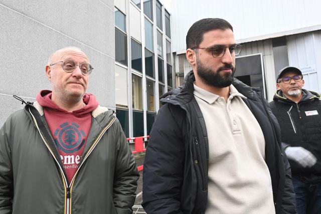 CFE-CGC trade union representative Jorge Carranho (L) and CGT trade union representative Khachatur Melkonyan (C) stand at the Brandt factory, in Vendome, central France on December 11, 2025 following the verdict of the court. On December 11, 2025, the court ordered the liquidation of the century-old home-appliance group Brandt, a flagship of French industry that has been in serious trouble since it was placed under court-supervised restructuring, the president of the Centre-Val de Loire region told AFP. (Photo by JEAN-FRANCOIS MONIER / AFP)