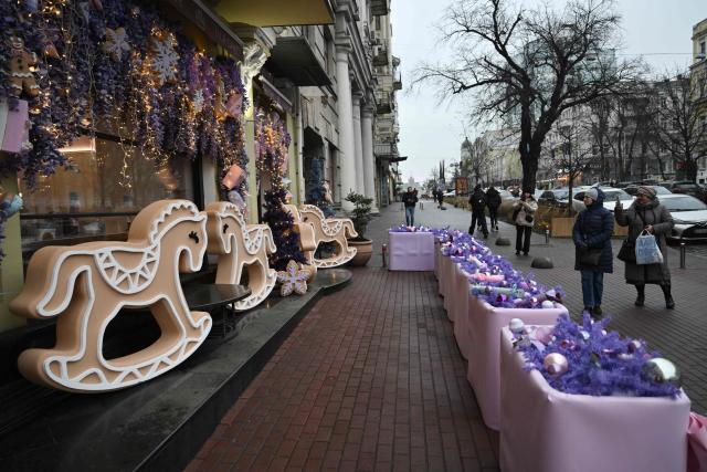 Pedestrians walk past Christmas decorations displayed onto the facade of a store on a street in central Kyiv on December 11, 2025, amid the Russian invasion of Ukraine. (Photo by Genya SAVILOV / AFP)