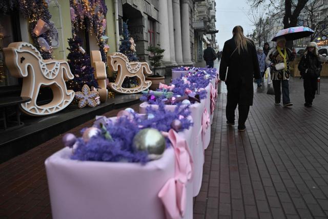 Pedestrians walk past Christmas decorations displayed onto the facade of a store on a street in central Kyiv on December 11, 2025, amid the Russian invasion of Ukraine. (Photo by Genya SAVILOV / AFP)