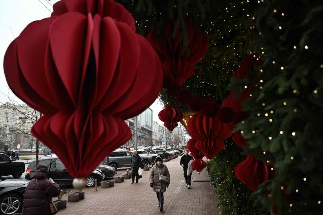 Pedestrians walk past Christmas decorations displayed onto the facade of a store on a street in central Kyiv on December 11, 2025, amid the Russian invasion of Ukraine. (Photo by Genya SAVILOV / AFP)