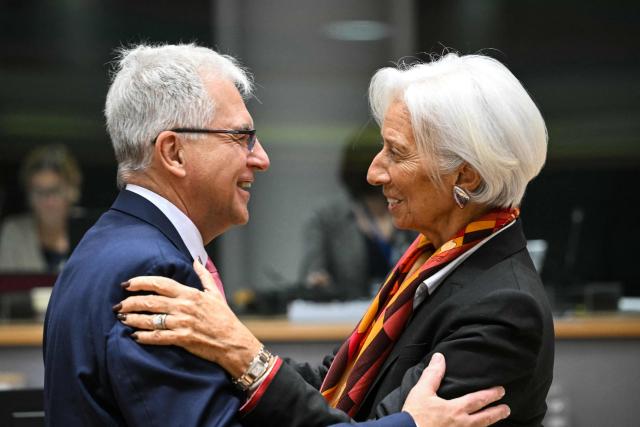 Director of the European Department at the International Monetary Fund Alfred Kammer (L) and European Central Bank (ECB) President Christine Lagarde (R) greet each other at the start of a meeting with finance ministers of the Eurozone to elect the new Eurogroup President and discuss the overall budgetary situation and the prospects of euro area, at the European Commission, in Brussels, on December 11, 2025. (Photo by NICOLAS TUCAT / AFP)