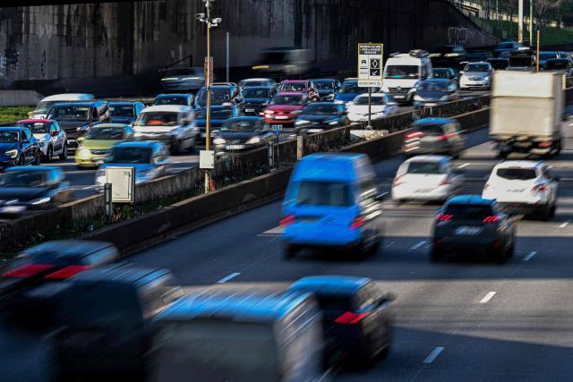 (FILES) This photograph taken in Paris on March 5, 2025 shows motorists driving their cars past a road sign announcing the new carpool lane on the Paris ring road. France is prepared to accept “targeted flexibilities” in the ban on the sale of new combustion engine and hybrid cars in the European Union from 2035, provided that they are accompanied by regulations encouraging production in Europe, according to a letter from five ministers seen by AFP on December 10, 2025. (Photo by Anna KURTH / AFP)