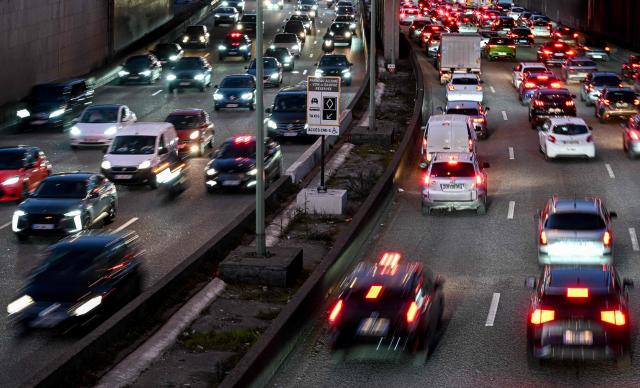 (FILES) This photograph taken in Paris on March 6, 2025 shows motorists driving their cars past a road sign announcing the new carpool lane on the Paris ring road. France is prepared to accept “targeted flexibilities” in the ban on the sale of new combustion engine and hybrid cars in the European Union from 2035, provided that they are accompanied by regulations encouraging production in Europe, according to a letter from five ministers seen by AFP on December 10, 2025. (Photo by Anna KURTH / AFP)