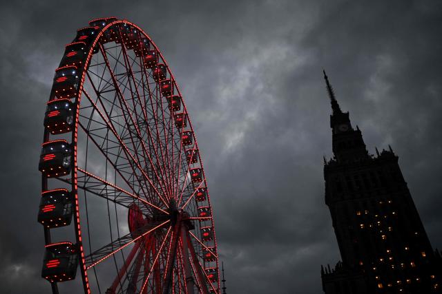 People ride a Ferris wheel in front of the Palace of Culture and Science at the Christmas market in Warsaw on December 11, 2025. (Photo by Sergei GAPON / AFP)