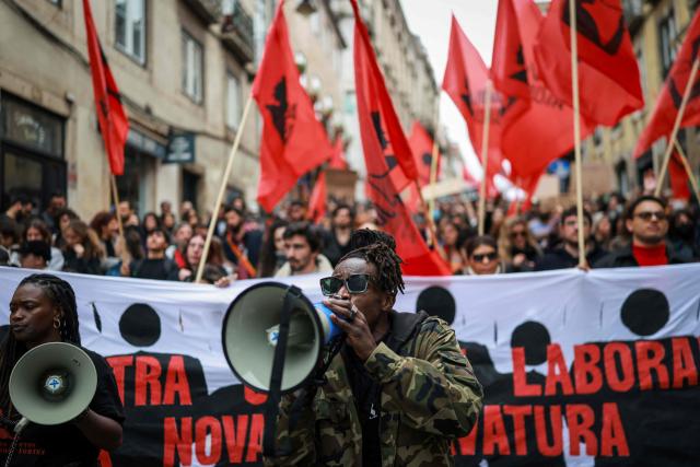 TOPSHOT - A man speaks in a megaphone during a demonstration during a general strike against a labour code reform project, called by the country's two main unions in Lisbon on December 11, 2025. Widespread disruption hit Portuguese air travel and trains, hospitals and schools as the unions called the biggest nationwide strike action for more than a decade, protesting against a draft law aiming to simplify firing procedures, extend the length of fixed-term contracts and expand the minimum services required during a strike. (Photo by PATRICIA DE MELO MOREIRA / AFP)