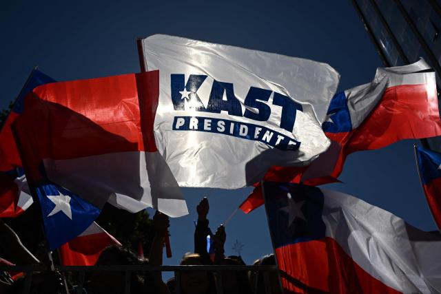 Supporters of Chile's presidential candidate Jose Antonio Kast wave national flags before the start of his closing campaign rally in Temuco, Chile, on December 11, 2025. The second round of the Chilean presidential election on December 14 will pit two candidates against each other who are diametrically opposed: Jeannette Jara, the representative of a broad left-wing coalition with modest origins, and the far-right leader Jose Antonio Kast, an ultraconservative Catholic determined to massively expel undocumented migrants. (Photo by Eitan ABRAMOVICH / AFP)