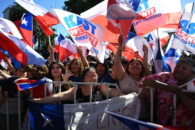 Supporters of Chile's presidential candidate Jose Antonio Kast wave flags before the start of his closing campaign rally in Temuco, Chile, on December 11, 2025. The second round of the Chilean presidential election on December 14 will pit two candidates against each other who are diametrically opposed: Jeannette Jara, the representative of a broad left-wing coalition with modest origins, and the far-right leader Jose Antonio Kast, an ultraconservative Catholic determined to massively expel undocumented migrants. (Photo by Eitan ABRAMOVICH / AFP)