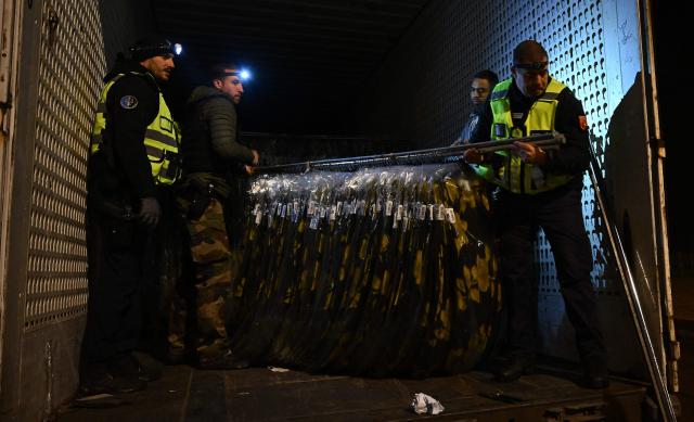 French gendarmes inspect unload merchandise from a truck during a control operation against drug trafficking at the A63 motorway tollbooth in Castets, south-western France on December 11, 2025. (Photo by Gaizka IROZ / AFP)