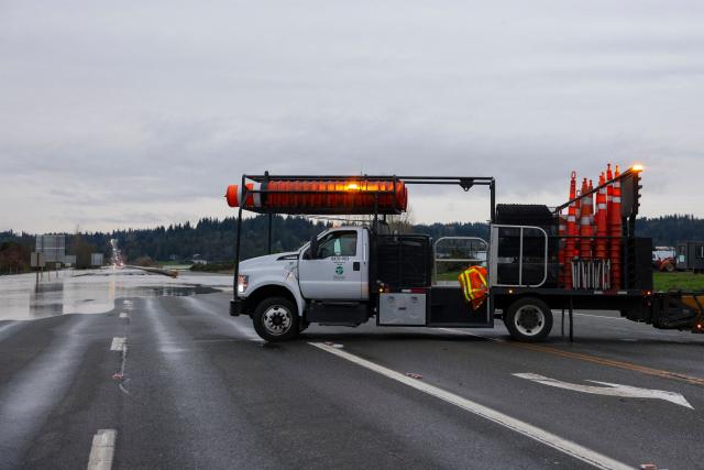 A Washington Department of Transportation vehicle is parked as flood waters from the Snohomish River cover a portion of State Route 9 in Snohomish, Washington, on December 11, 2025. Tens of thousands of people were under evacuation orders Thursday in western North America, after days of heavy rain forced rivers to burst their banks. Storms have battered Washington state in the US and British Columbia over the Canadian border for several days, with rivers continuing to rise. (Photo by Jason Redmond / AFP)