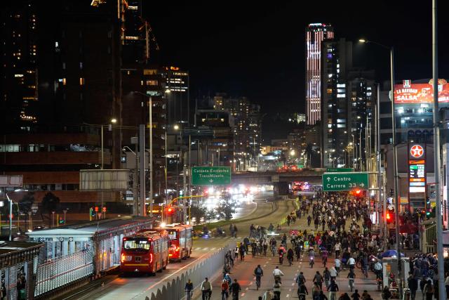 People ride bicycles during a car free night cycle way as part of Christmas celebrations in Bogota on December 11, 2025 (Photo by Sergio Angel / AFP)