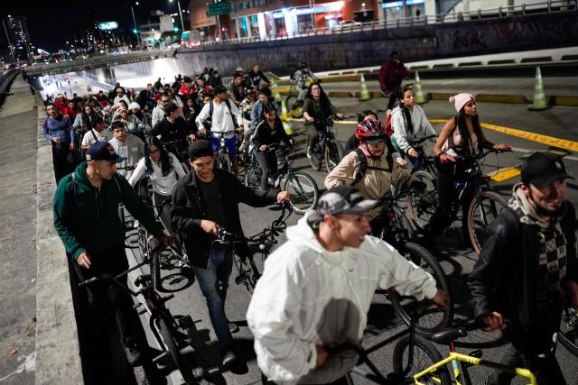 People ride bicycles during a car free night cycle way as part of Christmas celebrations in Bogota on December 11, 2025 (Photo by Sergio Angel / AFP)