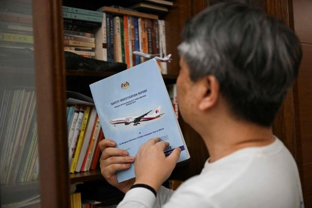 In this picture taken on December 10, 2025, Jiang Hui, whose mother was on board the missing Malaysia Airlines flight MH370, is seen showing documents of the accident at his home in Beijing. When Jiang Hui thinks of his mother, he remembers her waving goodbye as she left for her Malaysia Airlines flight, a bag slung across her shoulder and promising to return with souvenirs from her trip. Jiang Cuiyun, then a 72-year-old retiree, was one of 239 people aboard flight MH370 when it vanished from radar screens on March 8, 2014, en route from Kuala Lumpur to Beijing. (Photo by Pedro PARDO / AFP) / TO GO WITH AFP STORY:  China-Malaysia-aviation-accident, by Isabel Kua