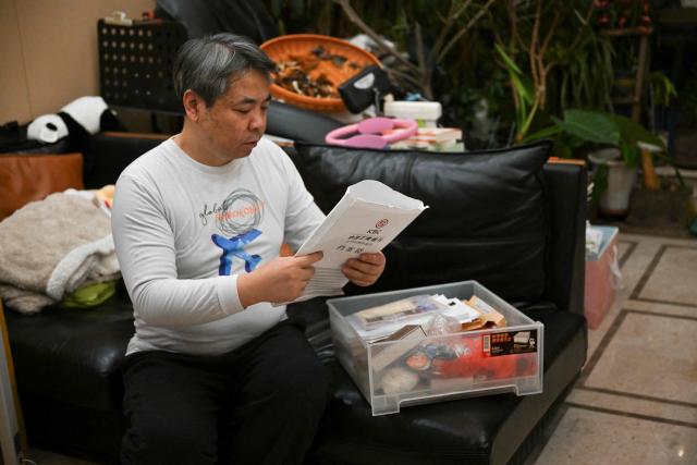 In this picture taken on December 10, 2025, Jiang Hui, whose mother was on board the missing Malaysia Airlines flight MH370, is seen showing documents of the accident at his home in Beijing. When Jiang Hui thinks of his mother, he remembers her waving goodbye as she left for her Malaysia Airlines flight, a bag slung across her shoulder and promising to return with souvenirs from her trip. Jiang Cuiyun, then a 72-year-old retiree, was one of 239 people aboard flight MH370 when it vanished from radar screens on March 8, 2014, en route from Kuala Lumpur to Beijing. (Photo by Pedro PARDO / AFP) / TO GO WITH AFP STORY:  China-Malaysia-aviation-accident, by Isabel Kua