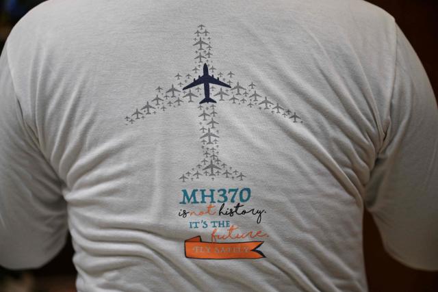 In this picture taken on December 10, 2025, Jiang Hui, whose mother was on board the missing Malaysia Airlines flight MH370, is seen wearing a t-shirt commemorating the accident at his home in Beijing. When Jiang Hui thinks of his mother, he remembers her waving goodbye as she left for her Malaysia Airlines flight, a bag slung across her shoulder and promising to return with souvenirs from her trip. Jiang Cuiyun, then a 72-year-old retiree, was one of 239 people aboard flight MH370 when it vanished from radar screens on March 8, 2014, en route from Kuala Lumpur to Beijing. (Photo by Pedro PARDO / AFP) / TO GO WITH AFP STORY:  China-Malaysia-aviation-accident, by Isabel Kua