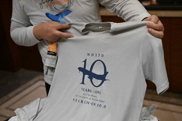 In this picture taken on December 10, 2025, Jiang Hui, whose mother was on board the missing Malaysia Airlines flight MH370, is seen showing items commemorating the accident at his home in Beijing. When Jiang Hui thinks of his mother, he remembers her waving goodbye as she left for her Malaysia Airlines flight, a bag slung across her shoulder and promising to return with souvenirs from her trip. Jiang Cuiyun, then a 72-year-old retiree, was one of 239 people aboard flight MH370 when it vanished from radar screens on March 8, 2014, en route from Kuala Lumpur to Beijing. (Photo by Pedro PARDO / AFP) / TO GO WITH AFP STORY:  China-Malaysia-aviation-accident, by Isabel Kua