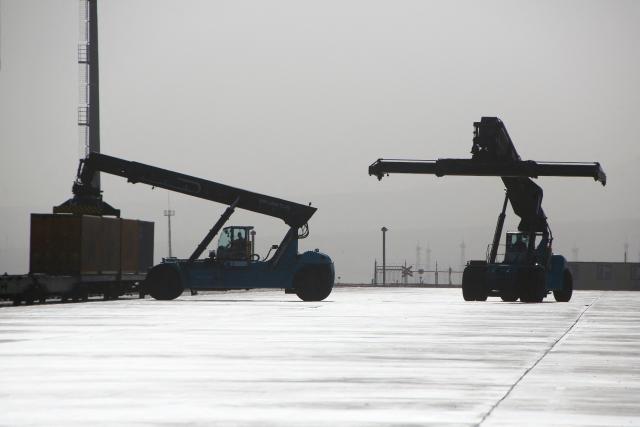A cargo lifter loads a container onto cars of a freight train at the railway station of Dostyk at the Kazakh-Chinese border, a key hub for trade between China and Europe through Central Asia, on November 19, 2025. (Photo by Ruslan PRYANIKOV / AFP)