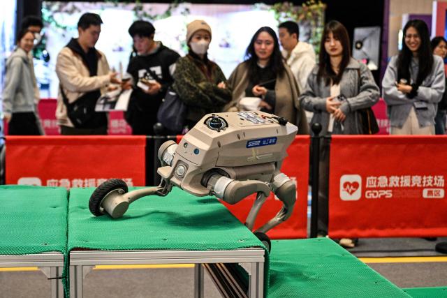 A remote-controlled robot trips while passing over obstacles at the Global Developer Pioneers Summit in Shanghai on December 12, 2025. (Photo by Hector RETAMAL / AFP)