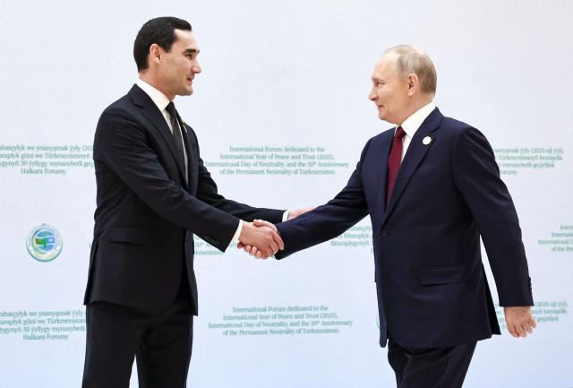 In this pool photograph distributed by the Russian state agency Sputnik, Turkmen President Serdar Berdymukhamedov welcomes Russia's President Vladimir Putin during an international forum dedicated to the 30th anniversary of Turkmenistan's "permanent neutrality" status in Ashgabat on December 12, 2025. (Photo by Alexander KAZAKOV / POOL / AFP)