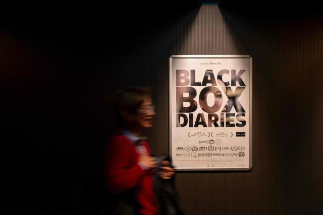 A woman walks in front of a promotional poster for the feature film "Black Box Diaries," by journalist and director Shiori Ito, on the first day of its release in Japan, at a movie theater in Tokyo on December 12, 2025. (Photo by Kazuhiro NOGI / AFP)