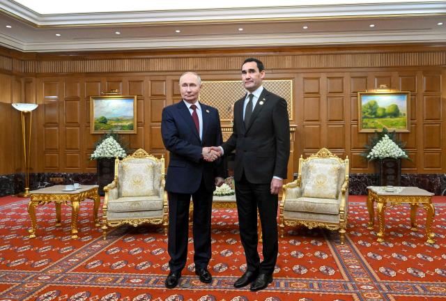 In this pool photograph distributed by the Russian state agency Sputnik, Russia's President Vladimir Putin and Turkmen President Serdar Berdymukhamedov hold a meeting in Ashgabat on December 12, 2025. (Photo by Kristina Kormilitsyna / POOL / AFP)