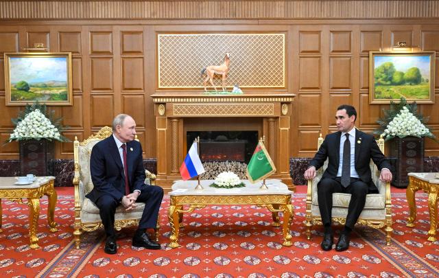 In this pool photograph distributed by the Russian state agency Sputnik, Russia's President Vladimir Putin and Turkmen President Serdar Berdymukhamedov hold a meeting in Ashgabat on December 12, 2025. (Photo by Kristina Kormilitsyna / POOL / AFP)