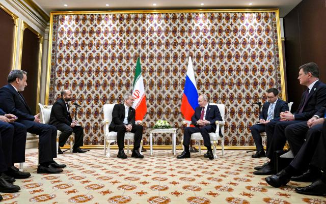 In this pool photograph distributed by the Russian state agency Sputnik, Russia's President Vladimir Putin and Iranian President Masoud Pezeshkian hold a meeting in Ashgabat on December 12, 2025. (Photo by Kristina Kormilitsyna / POOL / AFP)